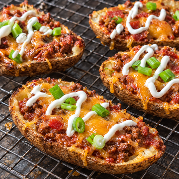 Chili stuffed potato skins topped with melted cheese, sour cream, and green onions